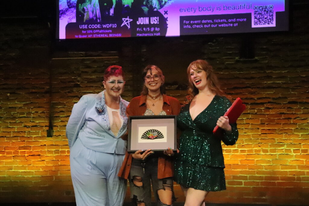Hosts and producers Joey March and Lady LaRouge present a framed Festival logo to graphic designer Mickey Lee during intermission.